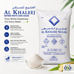 A large white bag of Al Khaleej Sugar refined cane sugar with Arabic and English text with product benefits icons, a small glass of sugar solution, and lemon slices.