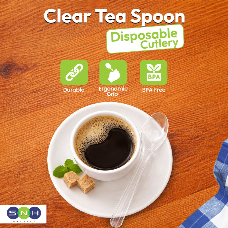 Clear tea spoon on a saucer with a cup of tea, placed on a wooden surface.
