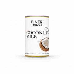 A cylindrical can of Finer Things Organic Coconut Milk on a plain white background. The can features a white label with black text, a gold horizontal line, and an illustration of a halved coconut showing its white flesh.