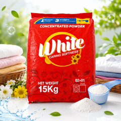 A 15kg red bag of White Caring Softness concentrated powder detergent, styled on a white surface with folded laundry, flowers, bubbles, and a scoop of white powder.
