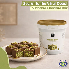 Pistachio chocolate bars on a plate with a container of pistachio sauce in the background, branded as All Things Food.