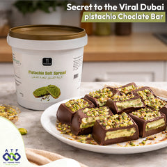 Pistachio chocolate bars on a plate with a container of pistachio soft spread in the background.