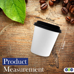 White paper cup with black lid on a wooden surface with coffee beans and a green leaf, showing measurements.